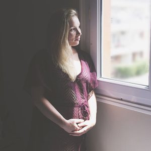 photographie de grossesse représentant une femme enceinte à côté d'une fenêtre
